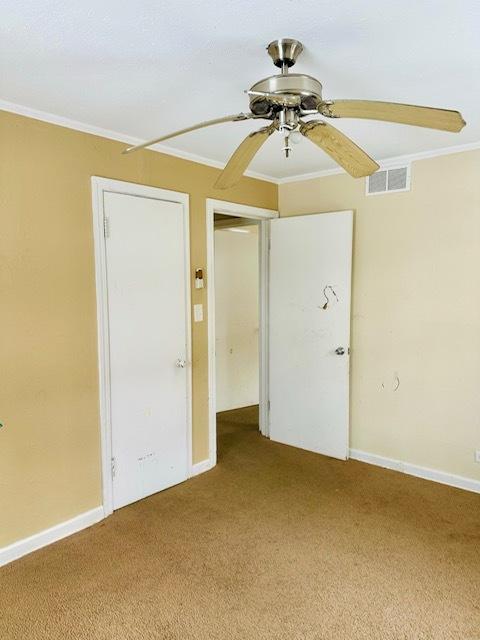 carpeted spare room featuring ceiling fan and ornamental molding