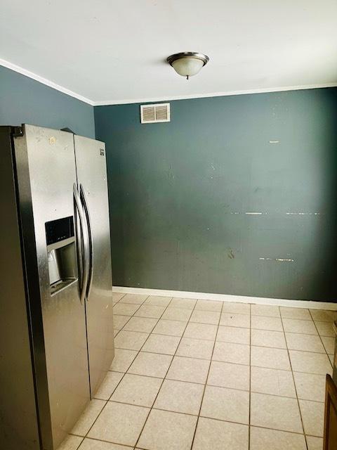 kitchen with light tile patterned floors, stainless steel fridge with ice dispenser, and crown molding