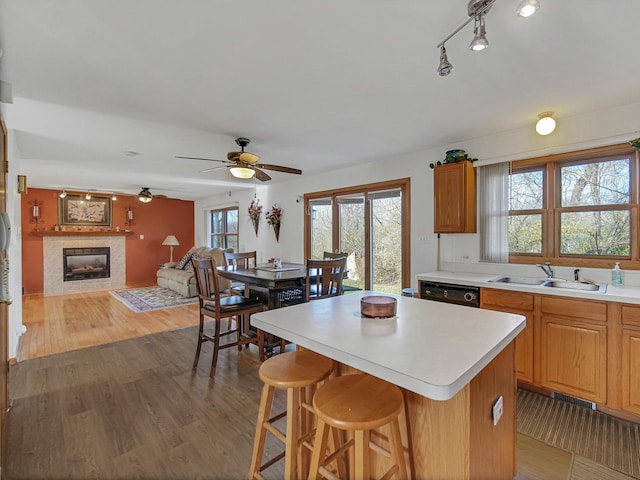 kitchen with ceiling fan, a fireplace, a center island, sink, and black dishwasher