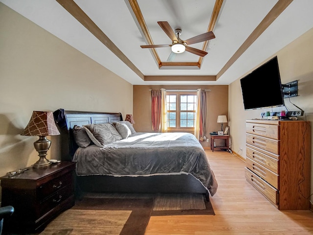 bedroom featuring ceiling fan, crown molding, light hardwood / wood-style flooring, and a raised ceiling