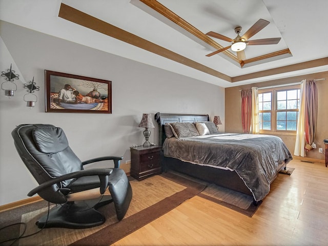 bedroom featuring ceiling fan, crown molding, a tray ceiling, and light hardwood / wood-style flooring