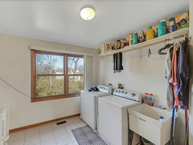 laundry area featuring light tile patterned floors, washer and dryer, and sink