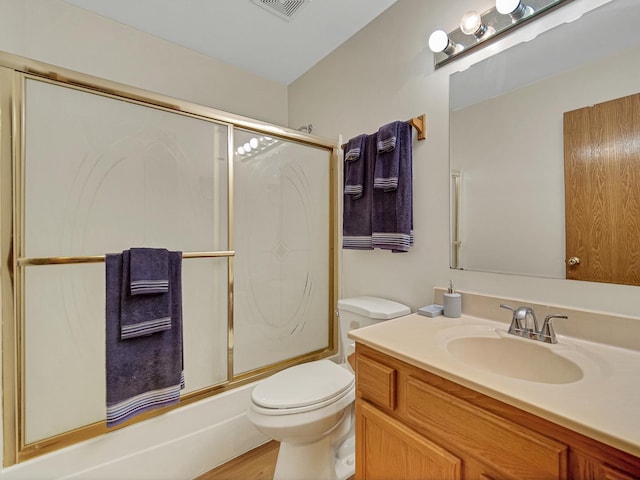 full bathroom featuring wood-type flooring, enclosed tub / shower combo, vanity, and toilet