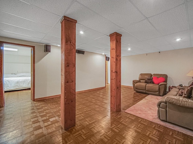 basement with a paneled ceiling and parquet flooring