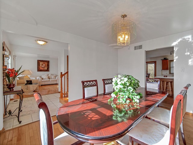 dining room featuring light wood-type flooring and an inviting chandelier