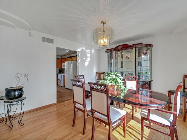 dining area with light wood-type flooring and a chandelier