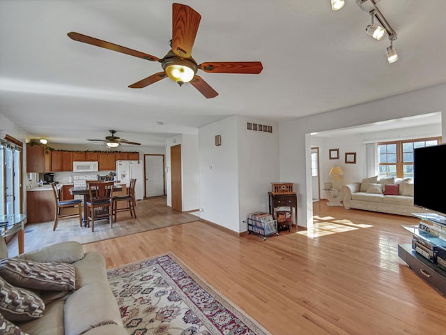 living room featuring ceiling fan, rail lighting, and light hardwood / wood-style flooring