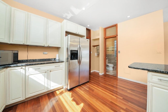 kitchen featuring white cabinetry, dark stone countertops, light hardwood / wood-style flooring, and appliances with stainless steel finishes