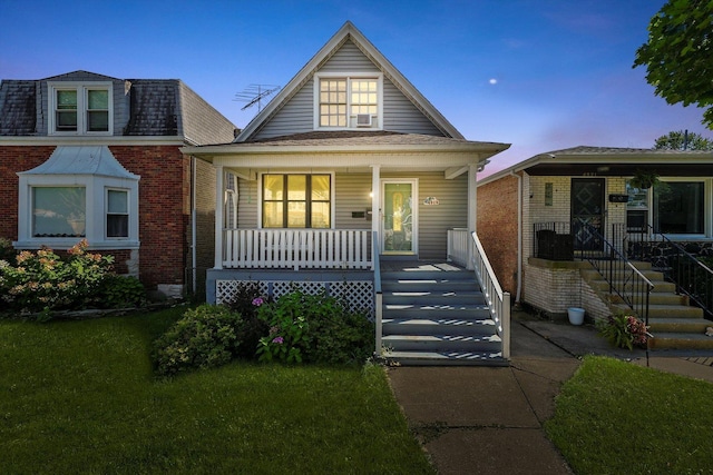 bungalow-style home with cooling unit, a yard, and covered porch