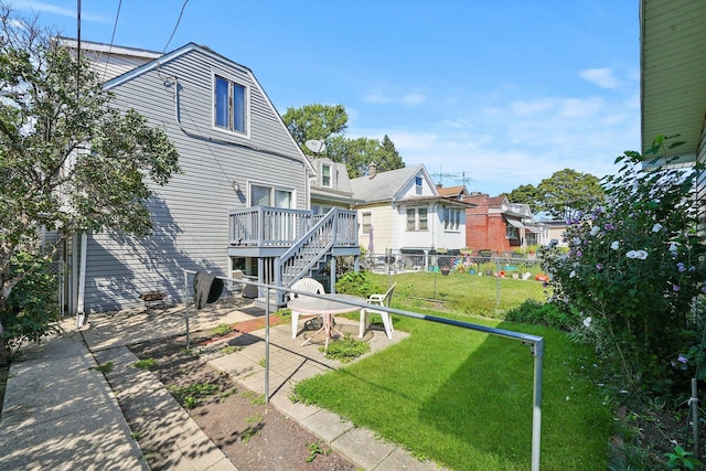 rear view of property featuring a deck, a yard, and a patio