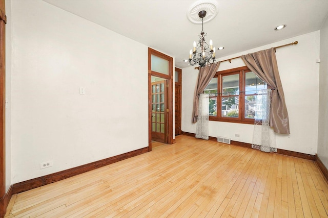 unfurnished dining area featuring a chandelier and light wood-type flooring