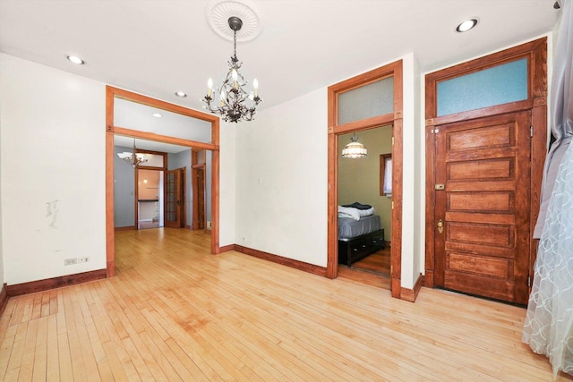 spare room with an inviting chandelier and light hardwood / wood-style floors