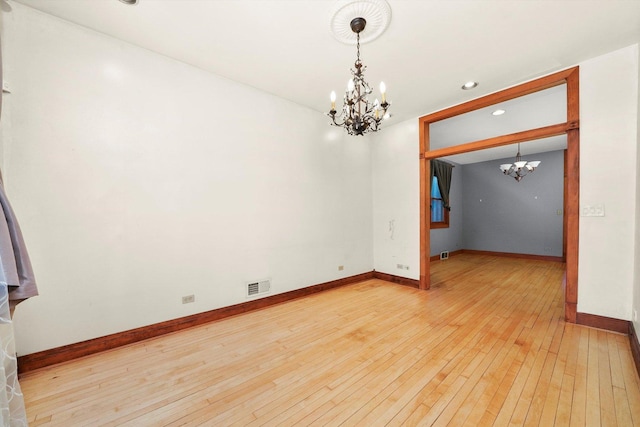 empty room featuring light hardwood / wood-style floors and a notable chandelier