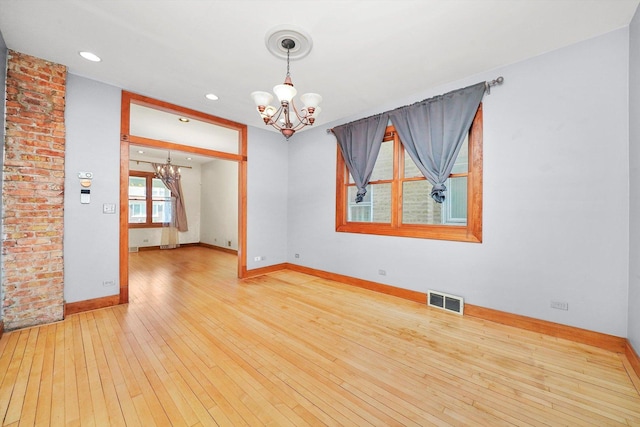 unfurnished room with wood-type flooring and an inviting chandelier