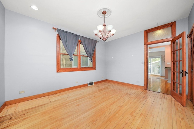 empty room with a notable chandelier and light hardwood / wood-style flooring