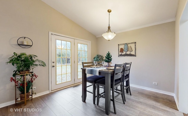 dining area with crown molding, lofted ceiling, and light hardwood / wood-style flooring