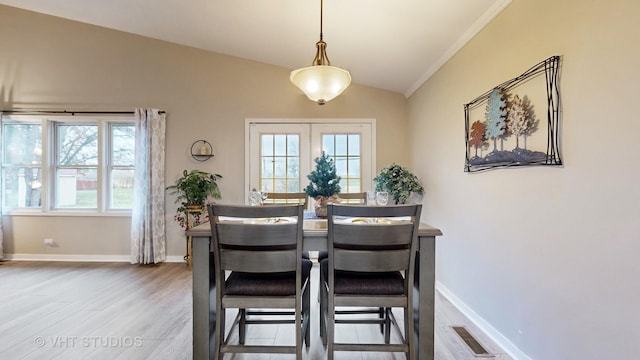 dining space with lofted ceiling, wood-type flooring, french doors, and a healthy amount of sunlight