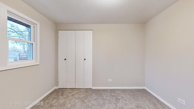 unfurnished bedroom featuring light carpet and a closet