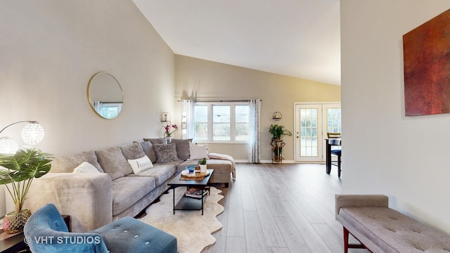 living room with vaulted ceiling, french doors, and light wood-type flooring