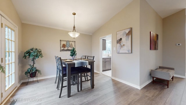 dining room with lofted ceiling, sink, and light hardwood / wood-style floors