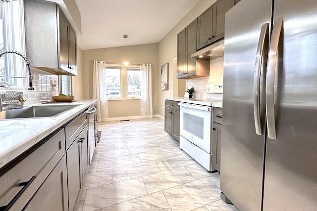 kitchen featuring vaulted ceiling, white electric range, sink, stainless steel fridge, and hanging light fixtures