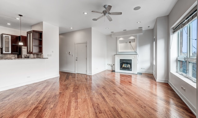 unfurnished living room featuring hardwood / wood-style flooring, plenty of natural light, and ceiling fan