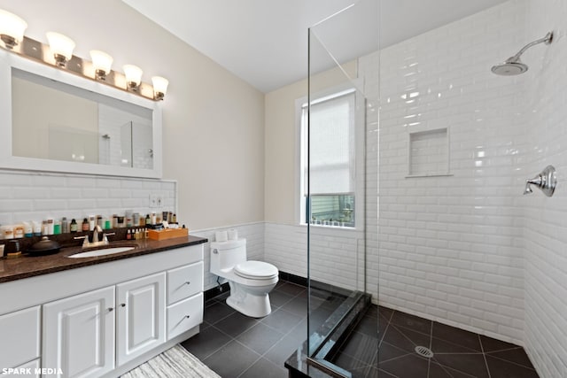 bathroom featuring tiled shower, tile walls, toilet, tile patterned floors, and vanity