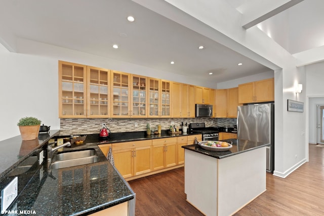 kitchen featuring a kitchen island, appliances with stainless steel finishes, dark stone countertops, and sink