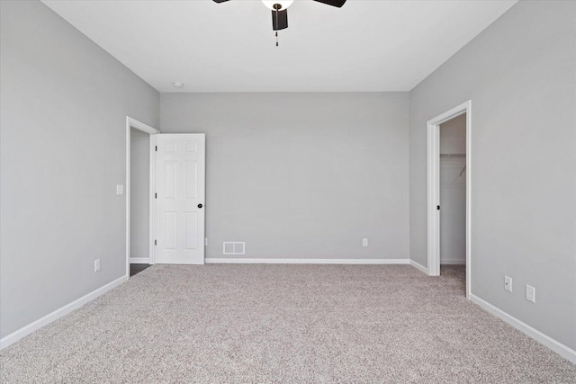 unfurnished bedroom with a spacious closet, a closet, ceiling fan, and carpet