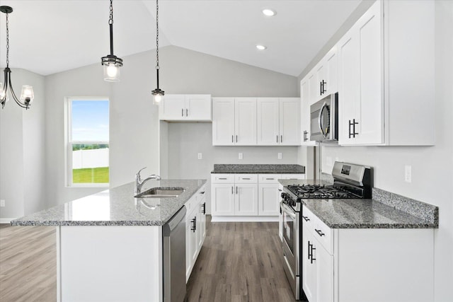 kitchen with sink, white cabinetry, hanging light fixtures, stainless steel appliances, and a kitchen island with sink