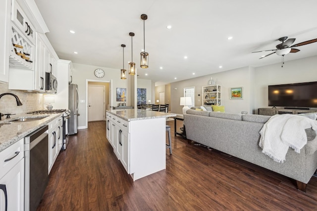 kitchen with a kitchen island, sink, white cabinets, and decorative light fixtures