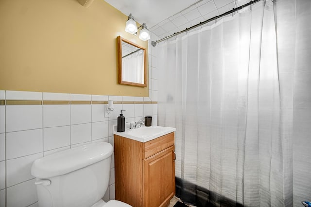 bathroom with toilet, vanity, and tile walls