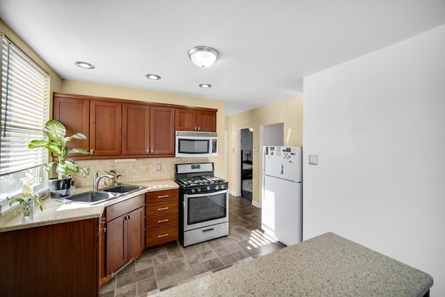 kitchen with sink, light stone countertops, backsplash, and appliances with stainless steel finishes