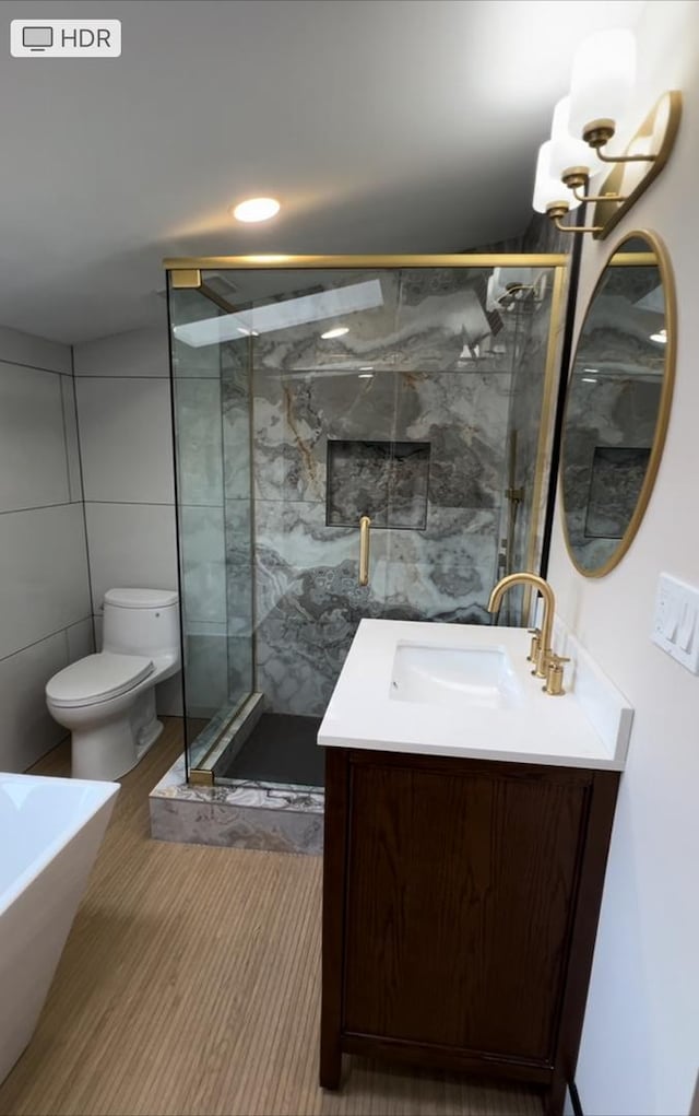 bathroom with toilet, an enclosed shower, vanity, and tile walls