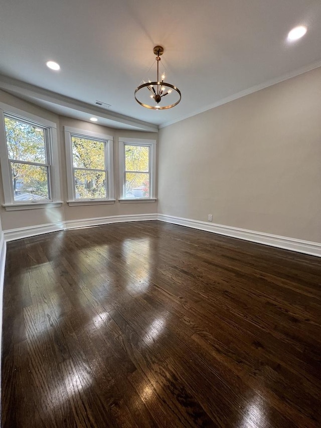 unfurnished room featuring dark hardwood / wood-style flooring, an inviting chandelier, and crown molding