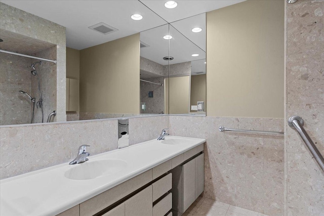 bathroom featuring tile patterned flooring, vanity, tile walls, and tiled shower