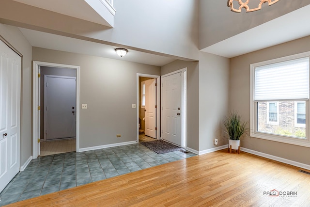 foyer with wood finished floors, visible vents, and baseboards