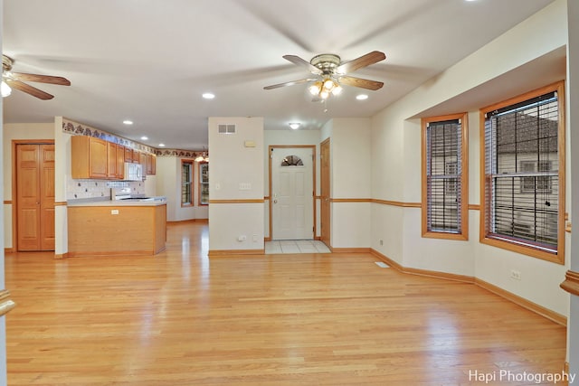 unfurnished living room featuring ceiling fan and light hardwood / wood-style floors