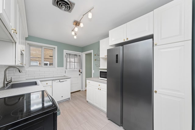 kitchen with white appliances, sink, tasteful backsplash, and white cabinetry