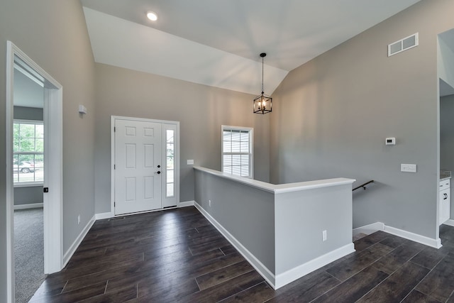 foyer featuring a chandelier, vaulted ceiling, and plenty of natural light