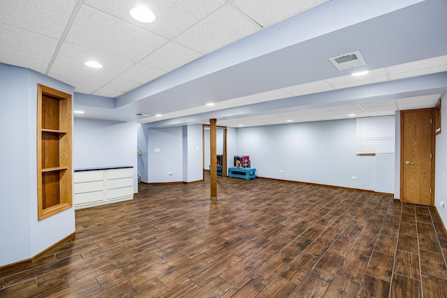 basement featuring a paneled ceiling and dark hardwood / wood-style flooring