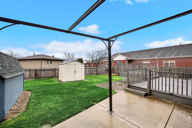 view of yard featuring a deck, a patio, and a storage unit