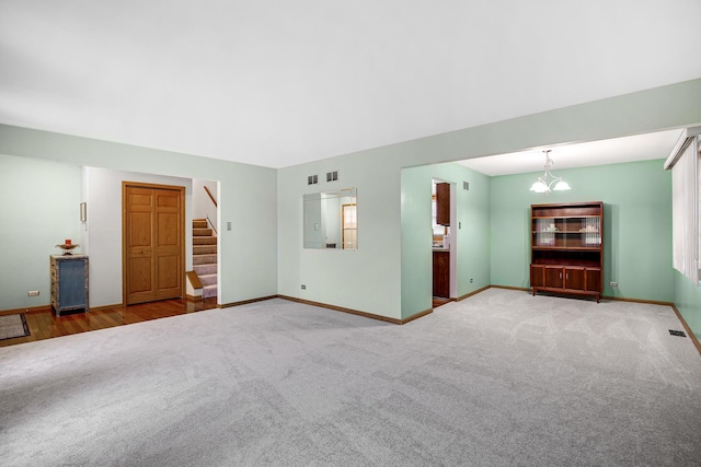 unfurnished living room featuring an inviting chandelier and carpet flooring