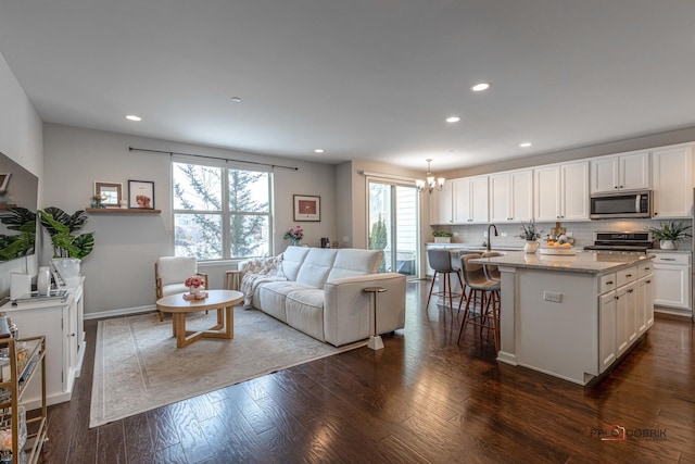 living room with dark hardwood / wood-style floors and an inviting chandelier