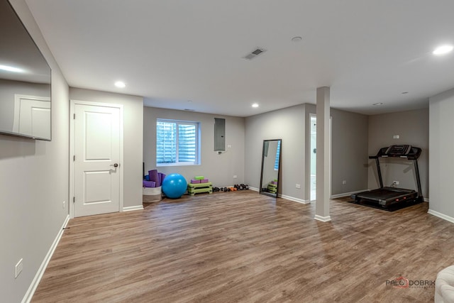 exercise area with light wood-type flooring and electric panel