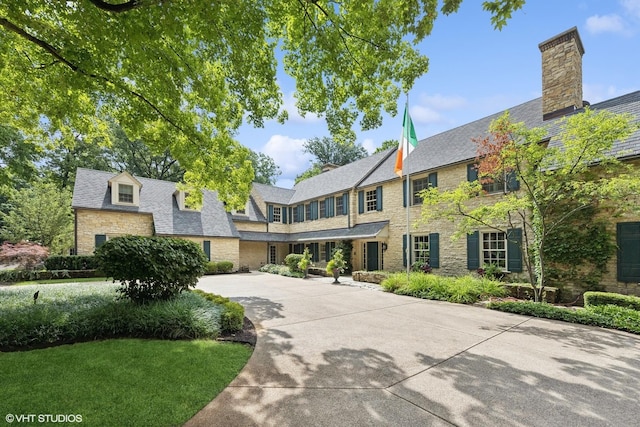 view of front of home with a high end roof, stone siding, and driveway