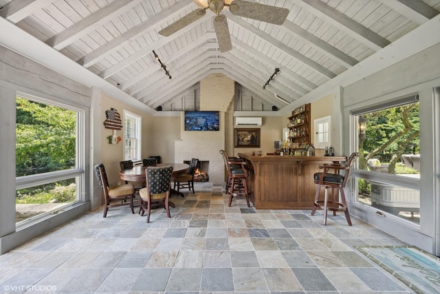 sunroom with ceiling fan, an AC wall unit, a healthy amount of sunlight, and vaulted ceiling with beams