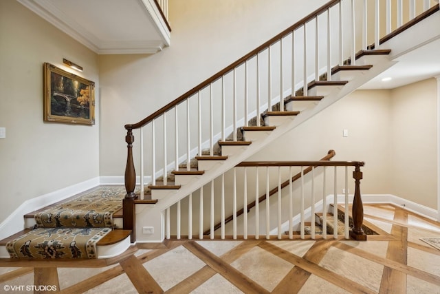 stairway with crown molding, a towering ceiling, and baseboards