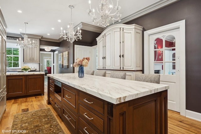 kitchen featuring light wood finished floors, a kitchen island, pendant lighting, and crown molding