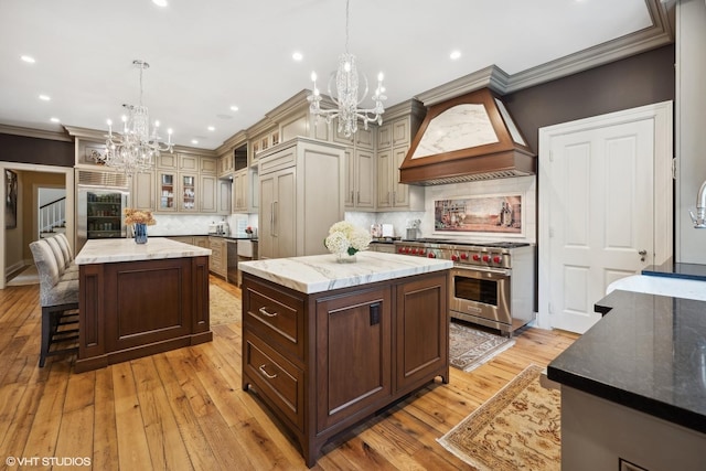 kitchen with a center island, custom range hood, a notable chandelier, and high quality appliances